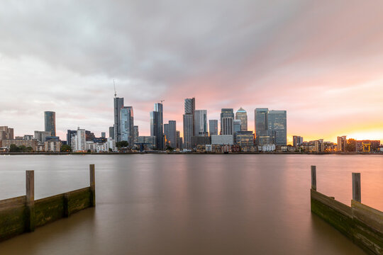 Modern skyline by Thames River in city against cloudy sky during sunset, London, UK
