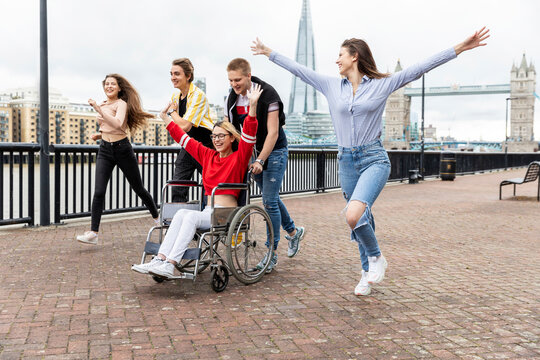 Carefree men and women with disabled female friend spending leisure time in city, London, UK