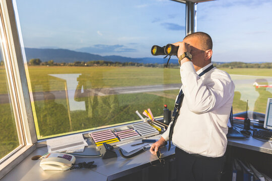 Pilot standing in control tower, using binoculars