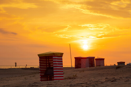 Striped tents at beach against orange sky during sunset