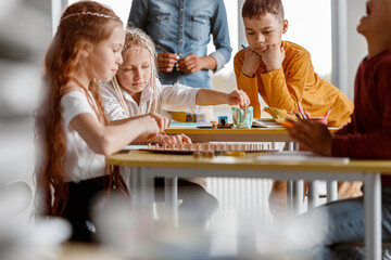 Kids with wooden mathematics tablet with rubber bands for practical exercises in preschool institutions