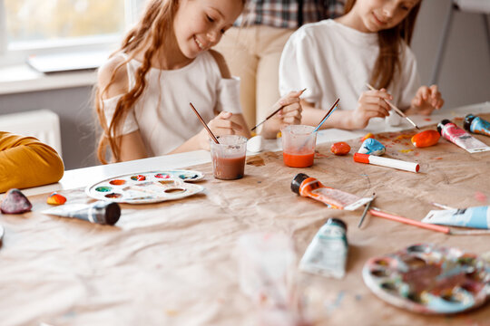 Smiling schoolgirls making art painting using water colors