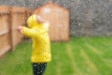 Woman enjoying rain with arms outstretched while standing in back yard during rainy season