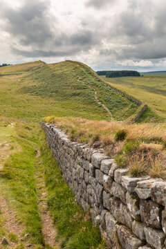UK, England, Hexham, Clouds over green grassy hills and part of Hadrians Wall