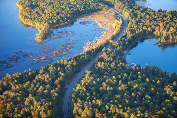 Aerial view of curving road between lakes and trees in autumn color in northern Minnesota