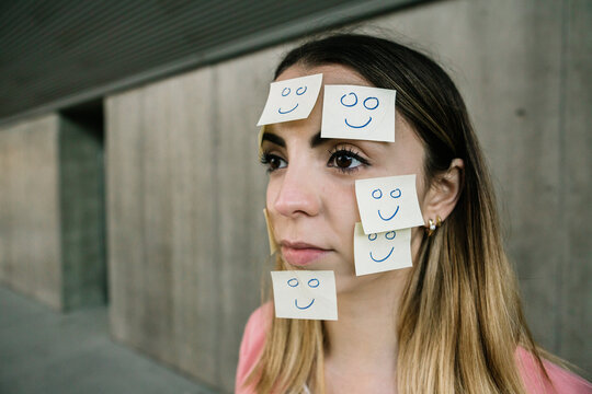 Portrait of serious woman wearing adhesive notes on face