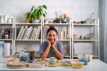 Asian woman learning color painting her self-made pottery at home. Confidence female enjoy hobbies and indoors leisure activity handicraft ceramic sculpture and painting workshop at pottery studio.