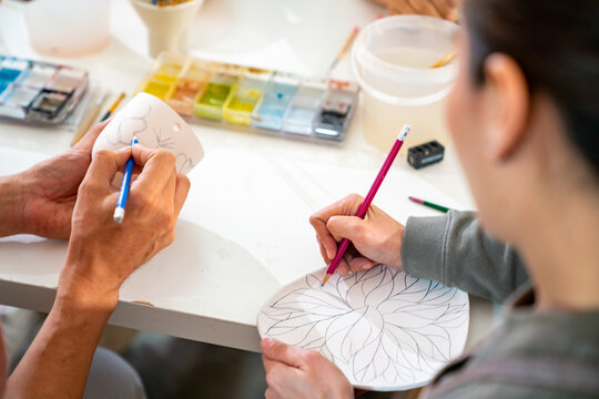 Group of Asian man and woman millennial generation friends enjoy and having fun painting self-made pottery together at pottery studio. Hobbies and leisure activity handmade ceramic painting workshop.