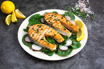 Plate of grilled salmon with lemon, radish and basil
