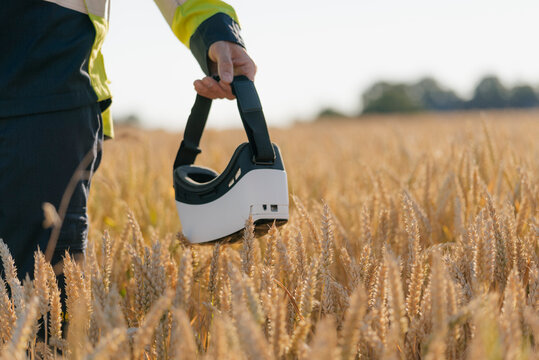 Close-up of man in protective workwear and VR glasses in a field