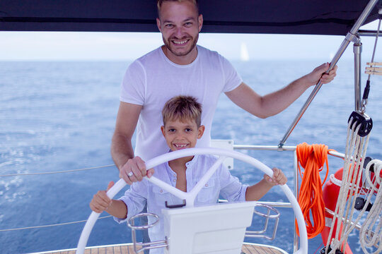 Father and son navigating sailing boat