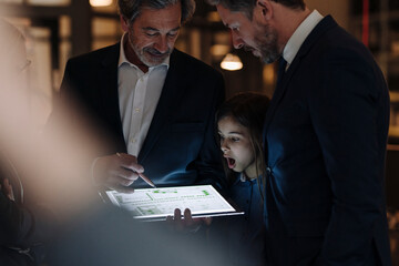 Business people and girl looking at shining tablet in office
