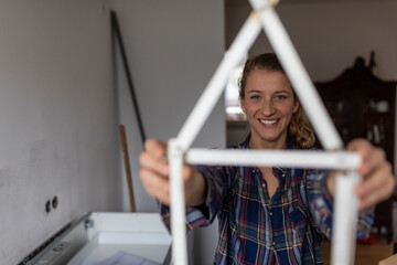 Happy young woman holding pocket rule in shape of a house