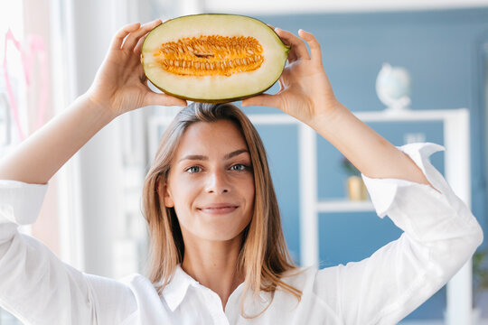 Young woman balancing half of a melon on her head
