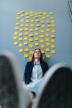 Young businesswoman sitting under data clound, relaxing with eyes closed