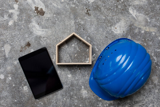 Digital tablet, safety hellmet and house model on gray ground