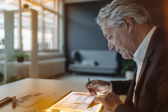 Senior businessman drawing on shining tablet