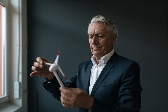 Senior businessman holding wind turbine model