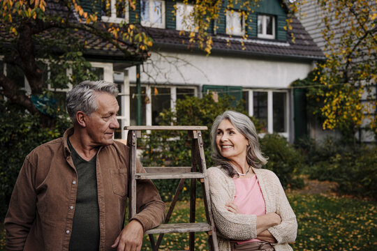 Senior couple with a ladder in garden of their home