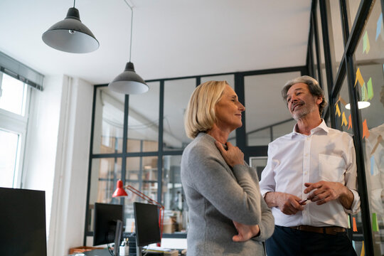 Businessman and businesswoman working on sticky notes at glass pane in office