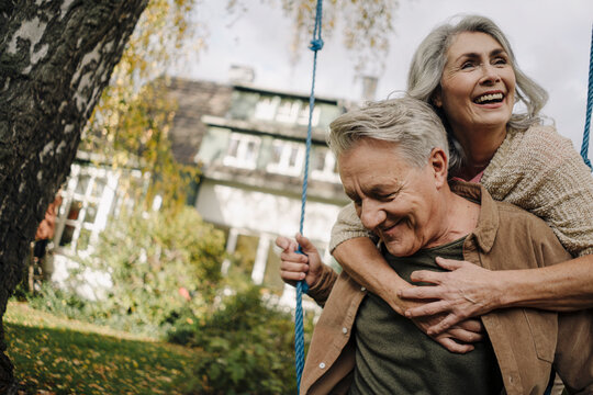 Happy woman embracing senior man on a swing in garden
