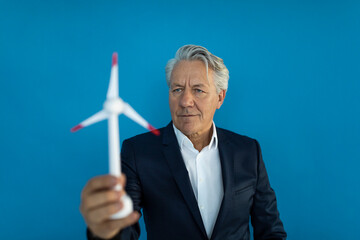Senior businessman holding wind turbine model