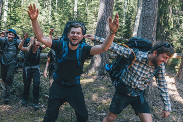 Young people backpacking in nature, laughing and waving at camera