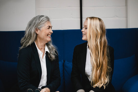 Happy mature and young businesswoman talking on couch