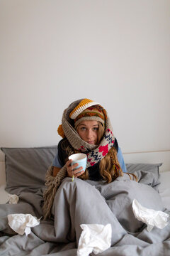 Ill young woman drinking tea in bed at home