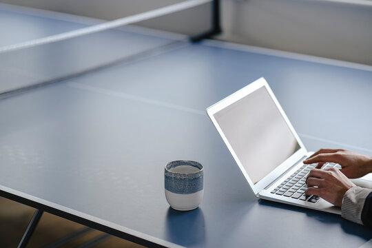 Close-up of businesswoman using laptop on table tennis table in office