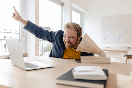 Happy businessman in office listening to music with a wooden gramophone