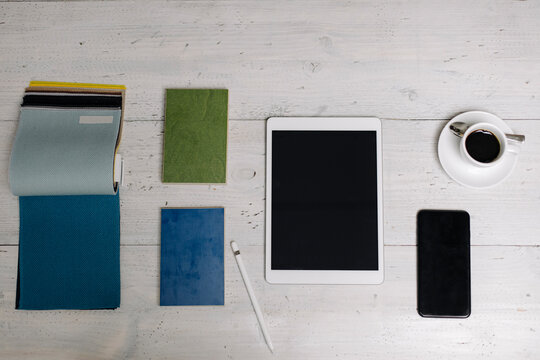 Tablet, cup of coffee, smartphone and samples on wooden surface