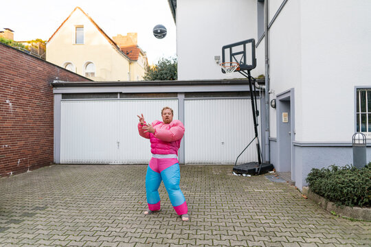 Portrait of a man with basketball wearing pink bodybuilder costume