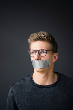 Portrait of young man with taped mouth