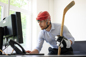 Businessman dressed up as ice hockey player working at desk in office