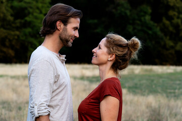 Happy couple in nature, standing face to face, smiling at each other