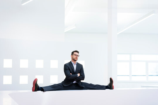 Businessman doing the splits on reception desk in office