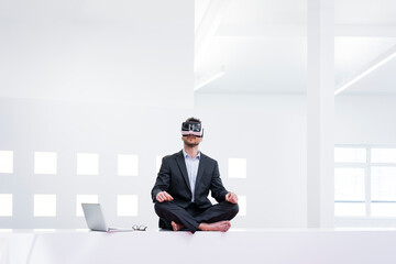 Businessman wearing VR glasses in office next to laptop