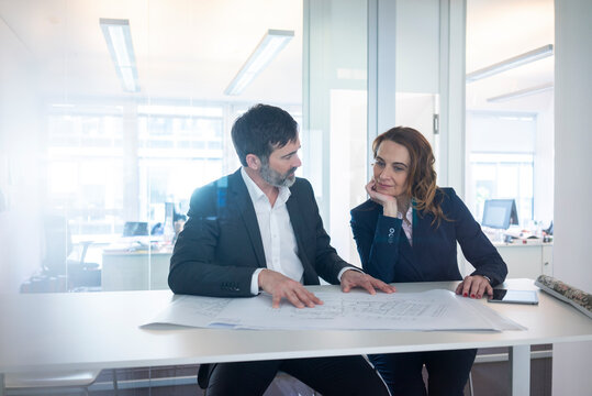 Businesswoman and businessman working on plan on desk in office