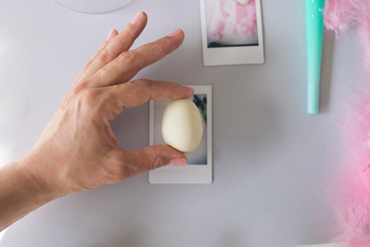 Hand holding an egg against polaroid image frame