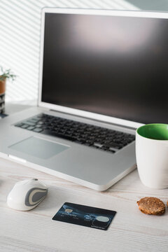 Office desk with computer mouse,  credit card, coffee mug and cookies