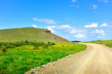 Fototapeta na wymiar Field road among the mountains of Khakassia