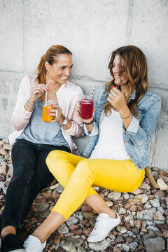 Two female friends drinking smoothies outdoors having fun