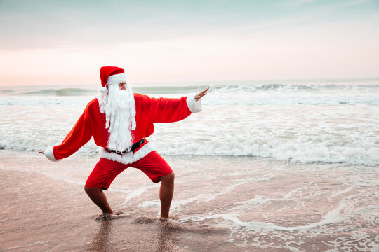 Thailand, man dressed up as Santa Claus posing on the beach at sunset