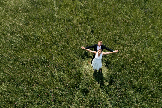 Aerial view of pregnant bride with her husband on a meadow