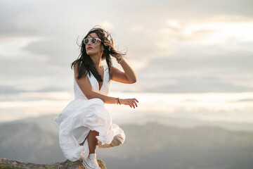 Young woman wearing white dress on viewpoint at sunset