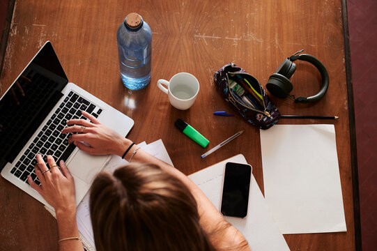 Female student studying at home, using laptop