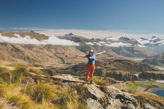Woman standing with outstretched arms on mountain top, Roys Peak, Lake Wanaka, New Zealand
