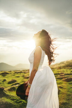 Young woman wearing white dress on viewpoint at sunset