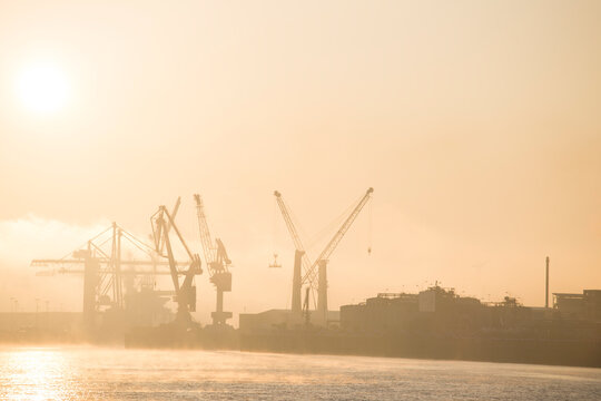 Germany, Hamburg, Silhouettes of harbor cranes&Ocirc;&oslash;&Omega;at sunrise